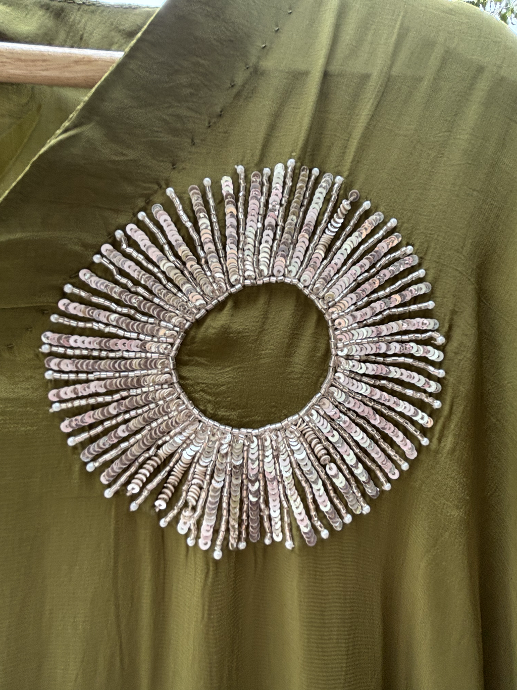 Decorative circular embellishment on a green fabric background