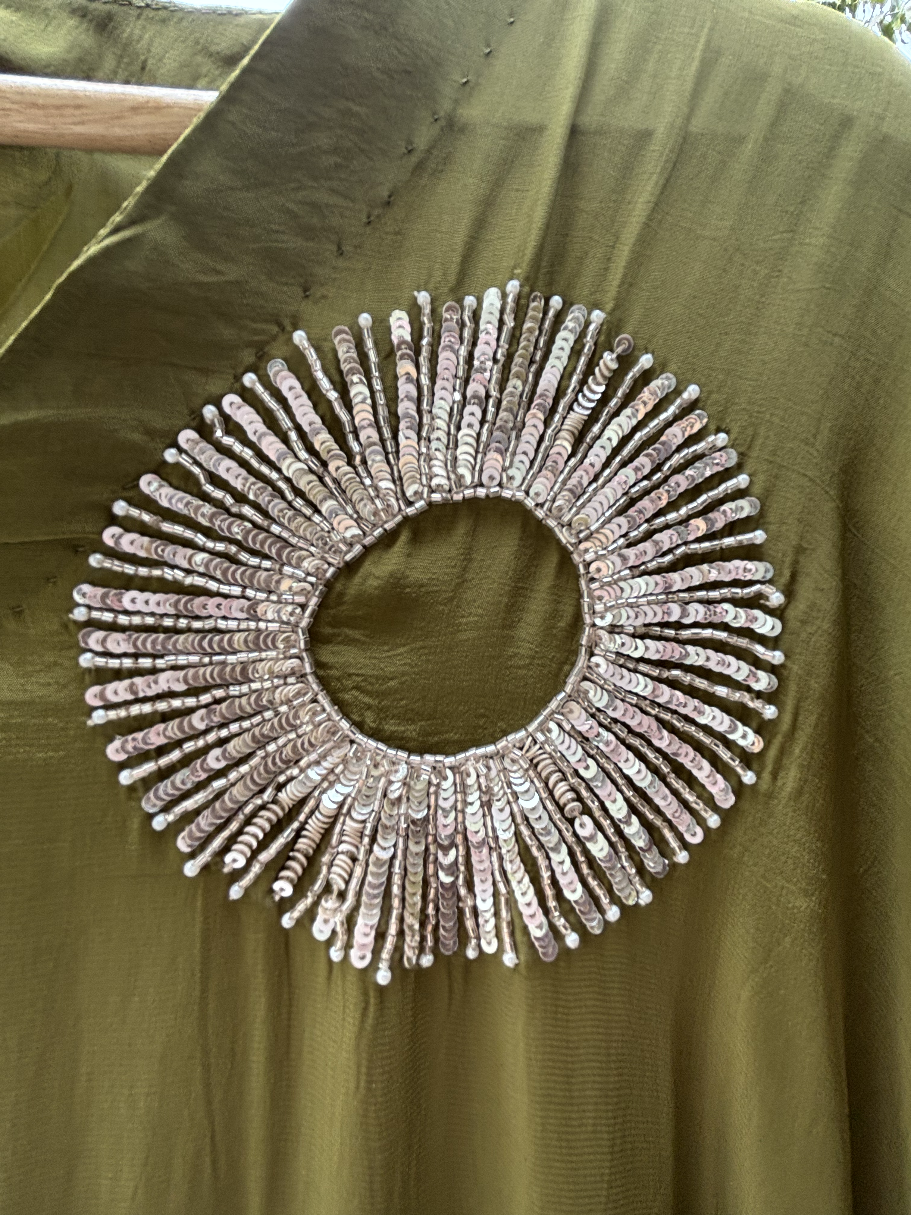 Decorative circular embellishment on a green fabric background