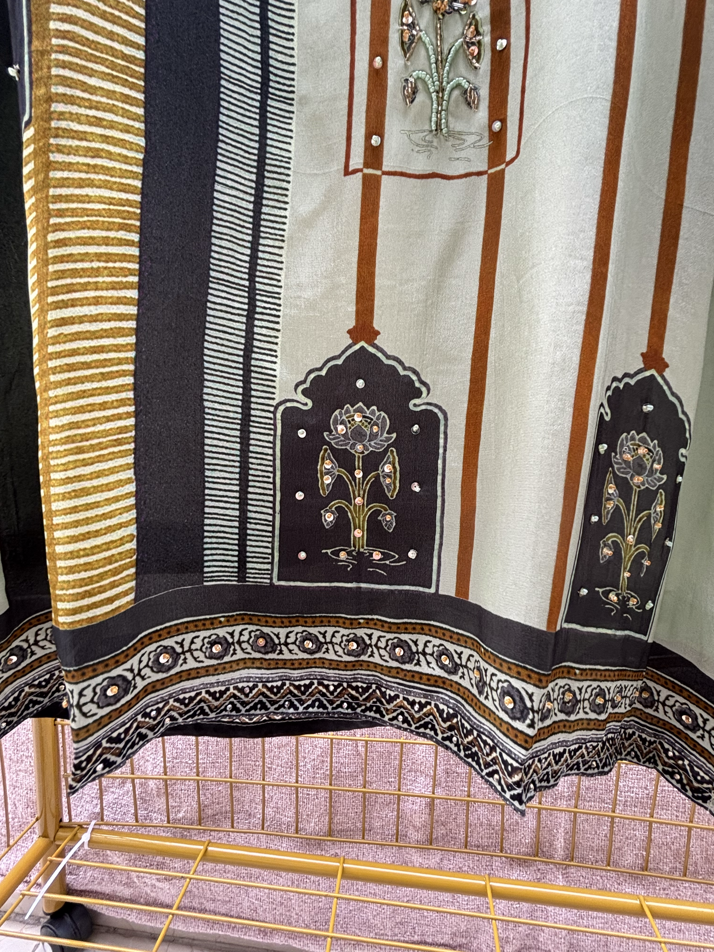 Decorative fabric with floral patterns and embroidery on a stand.