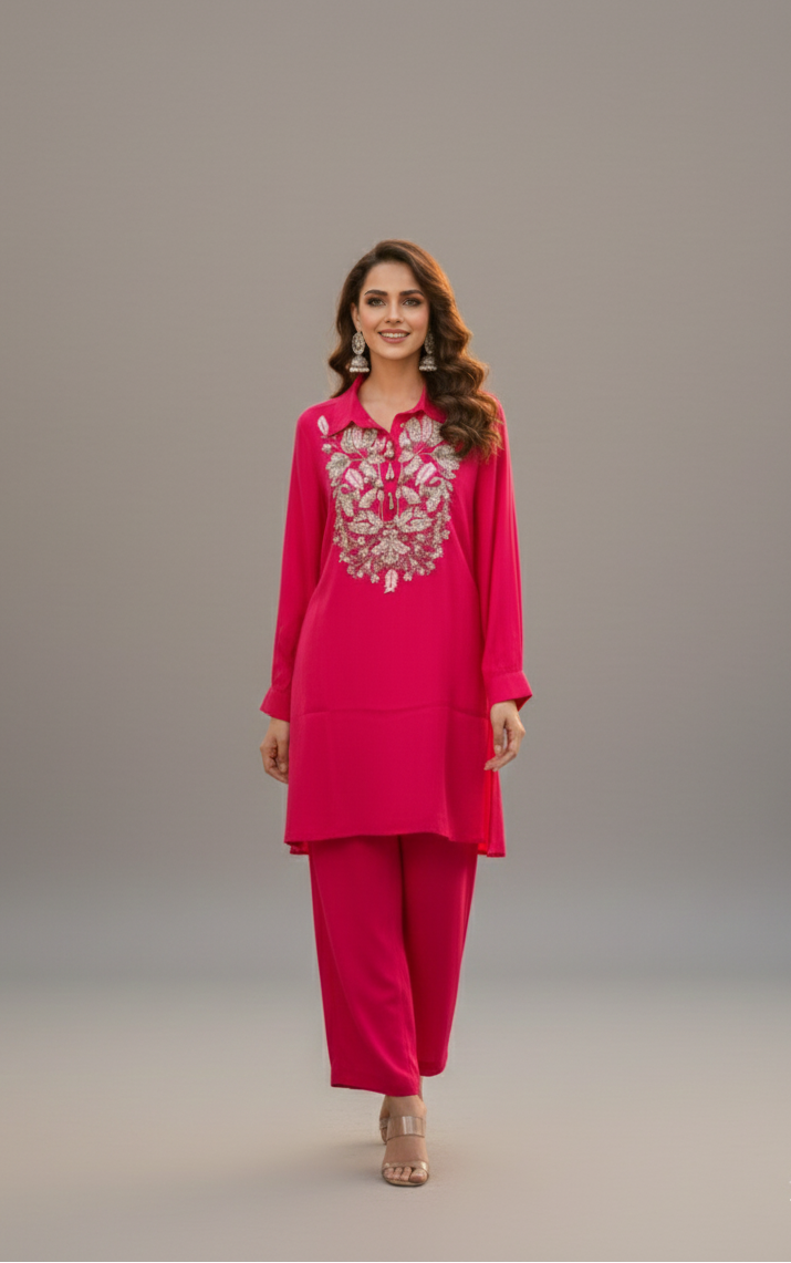 Woman wearing a pink traditional outfit with intricate embroidery on a gray background