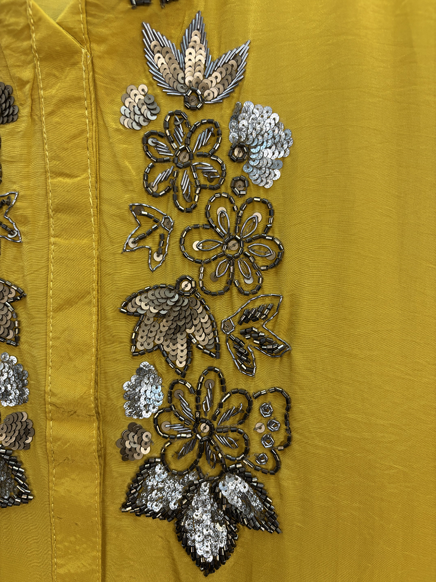 Close-up of a yellow fabric with floral sequin patterns
