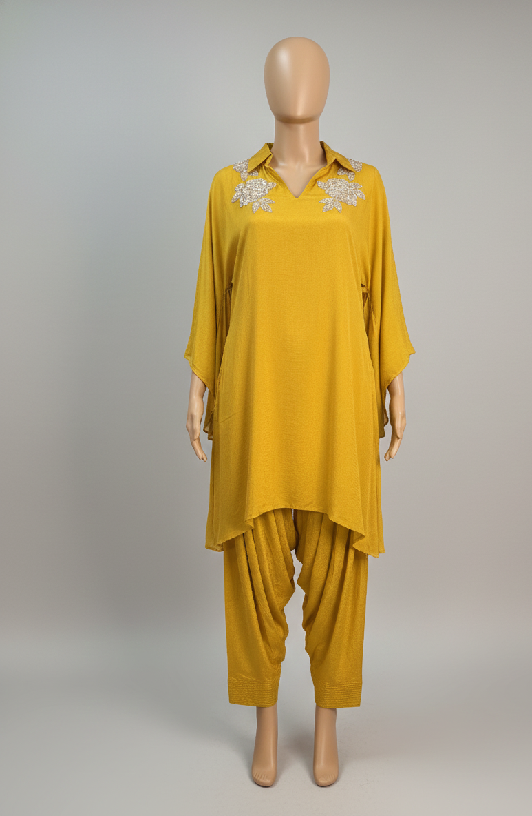 Mannequin wearing a mustard yellow outfit with lace details on a gray background