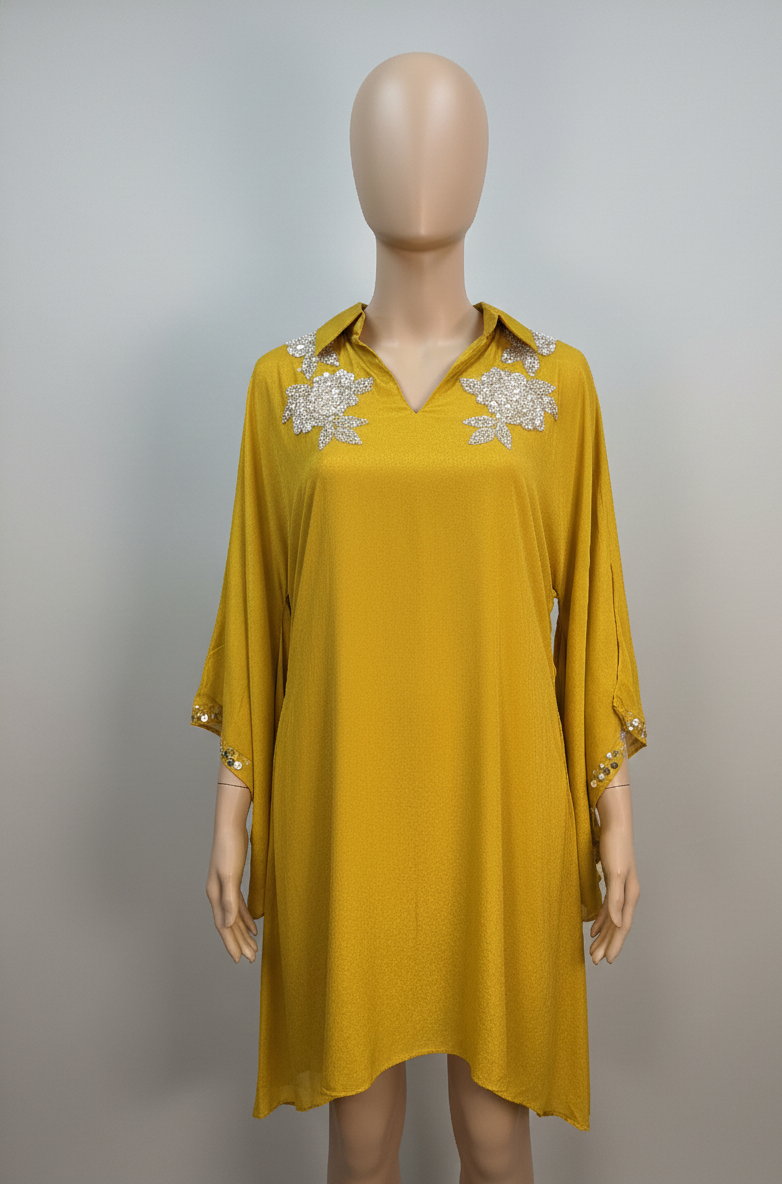 Mustard yellow dress with floral embellishments on a mannequin against a gray background