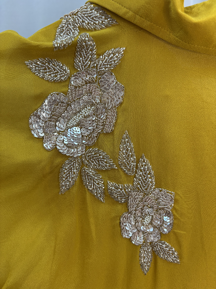 Mustard yellow fabric with silver floral embroidery on a plain background
