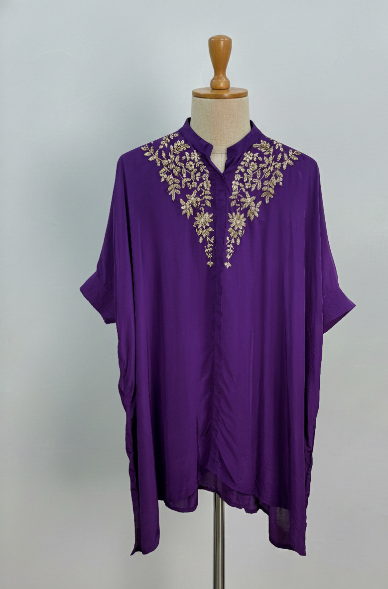 Purple top with gold embroidery on a mannequin against a gray background