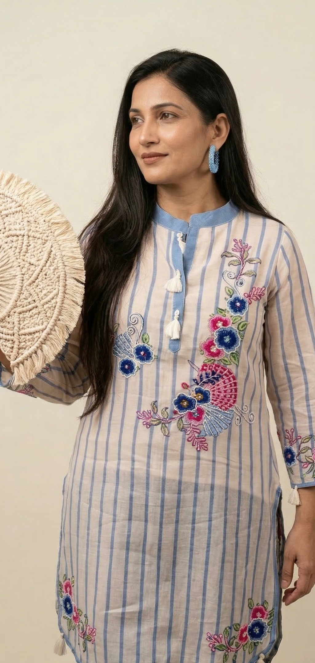 Woman wearing a floral embroidered dress holding a woven basket against a plain background