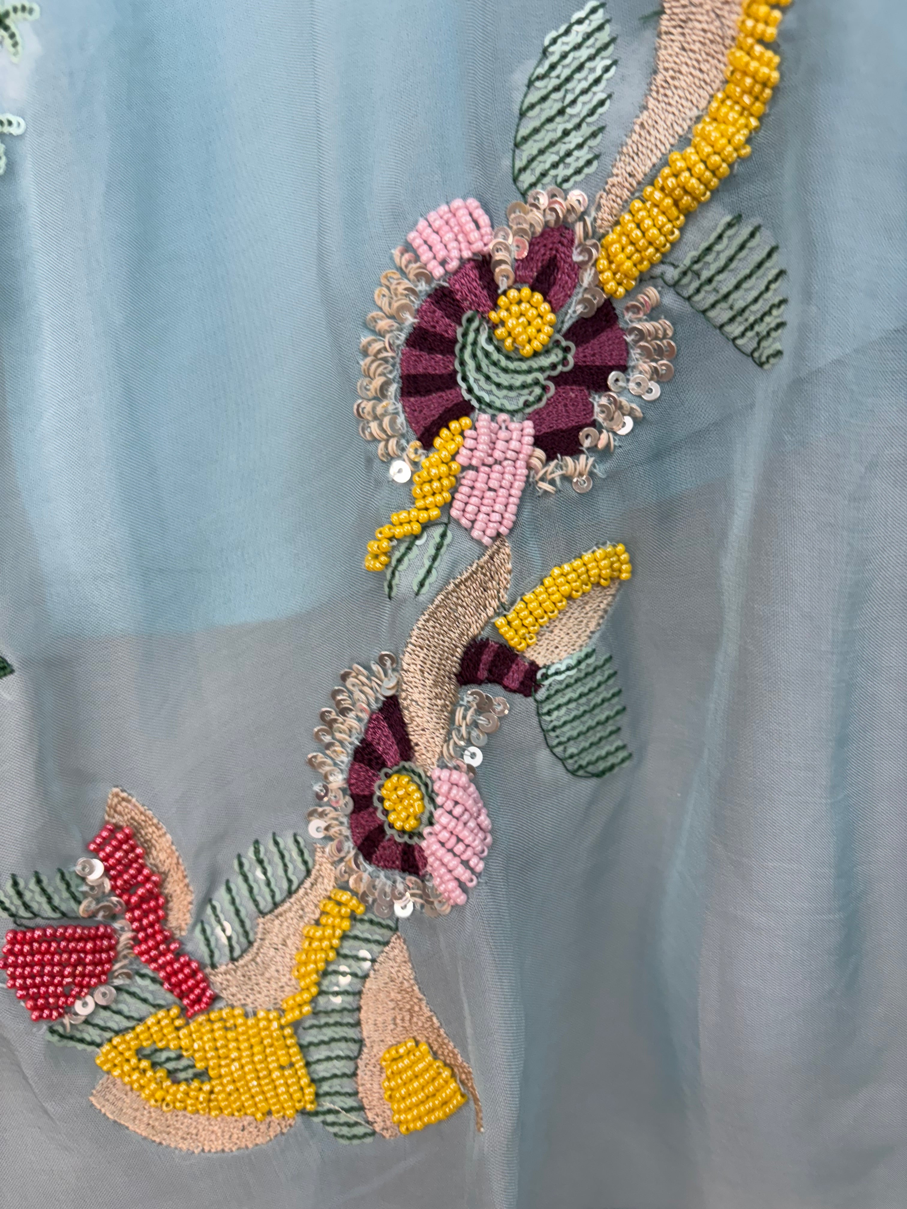 Decorative headband with floral design and colorful beads on a light blue fabric background