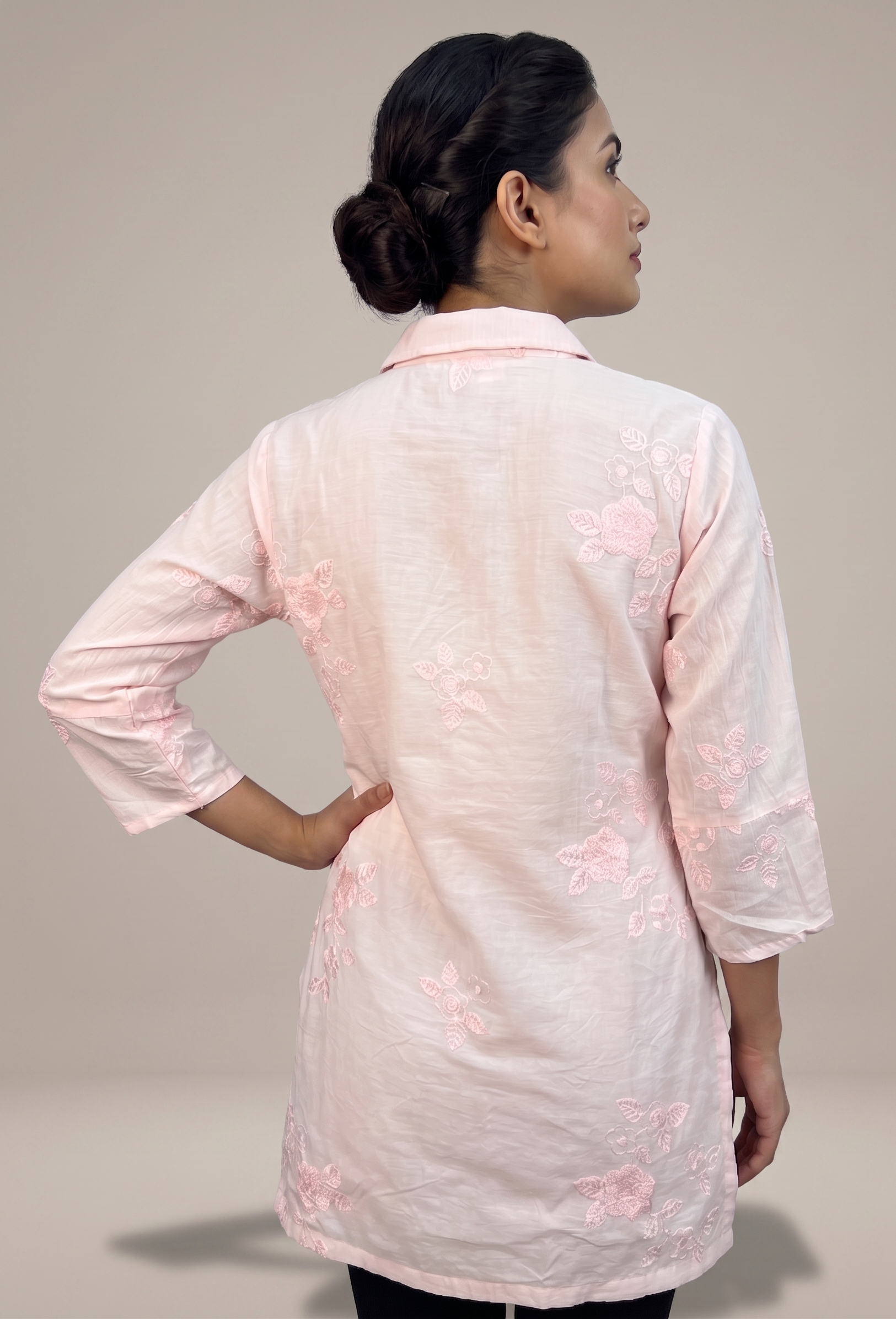 Woman wearing a light pink embroidered kurta against a neutral background