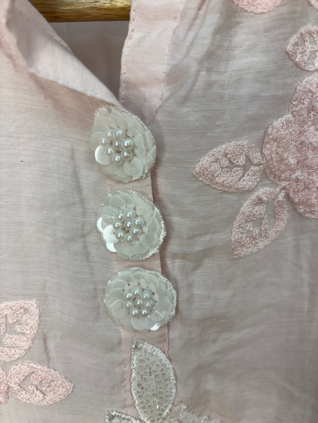 Close-up of embroidered fabric with floral patterns on a light background