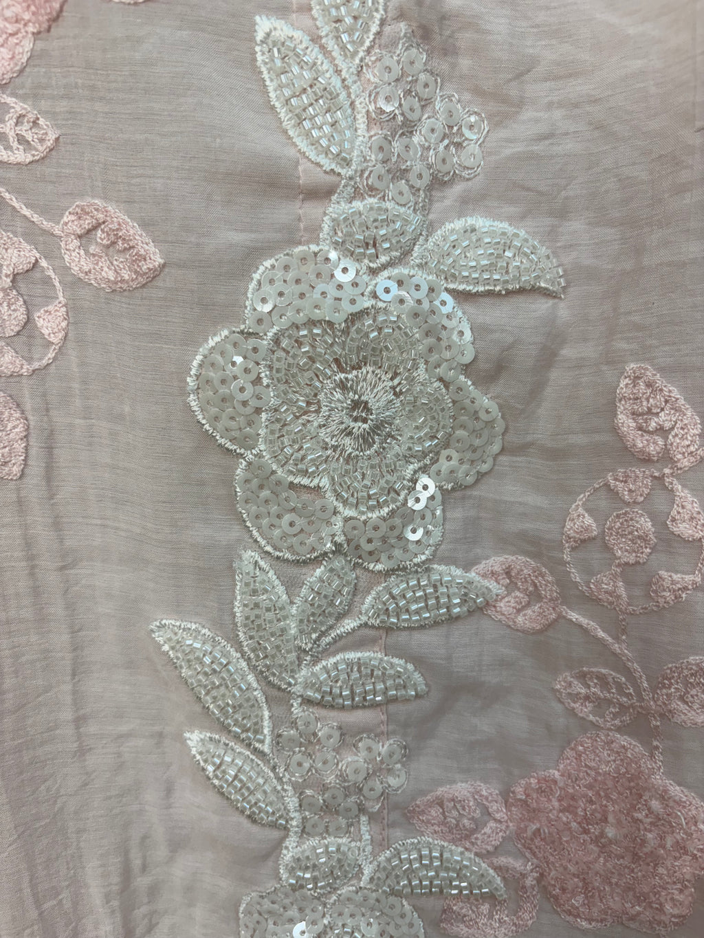Decorative floral pattern with beads and sequins on a gray fabric background