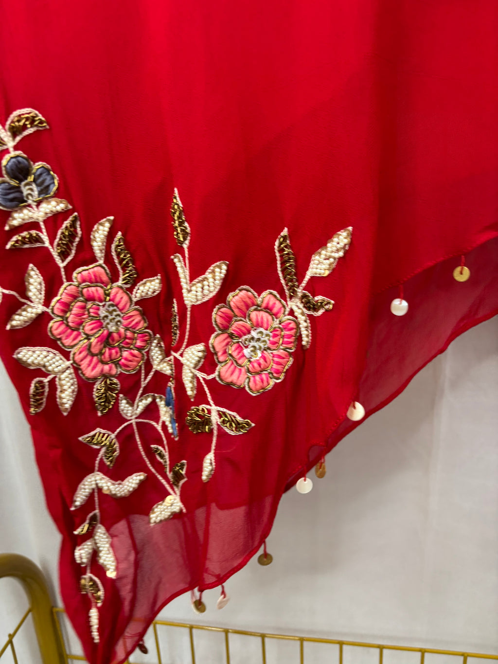 Red fabric with floral embroidery and tassels on a white background