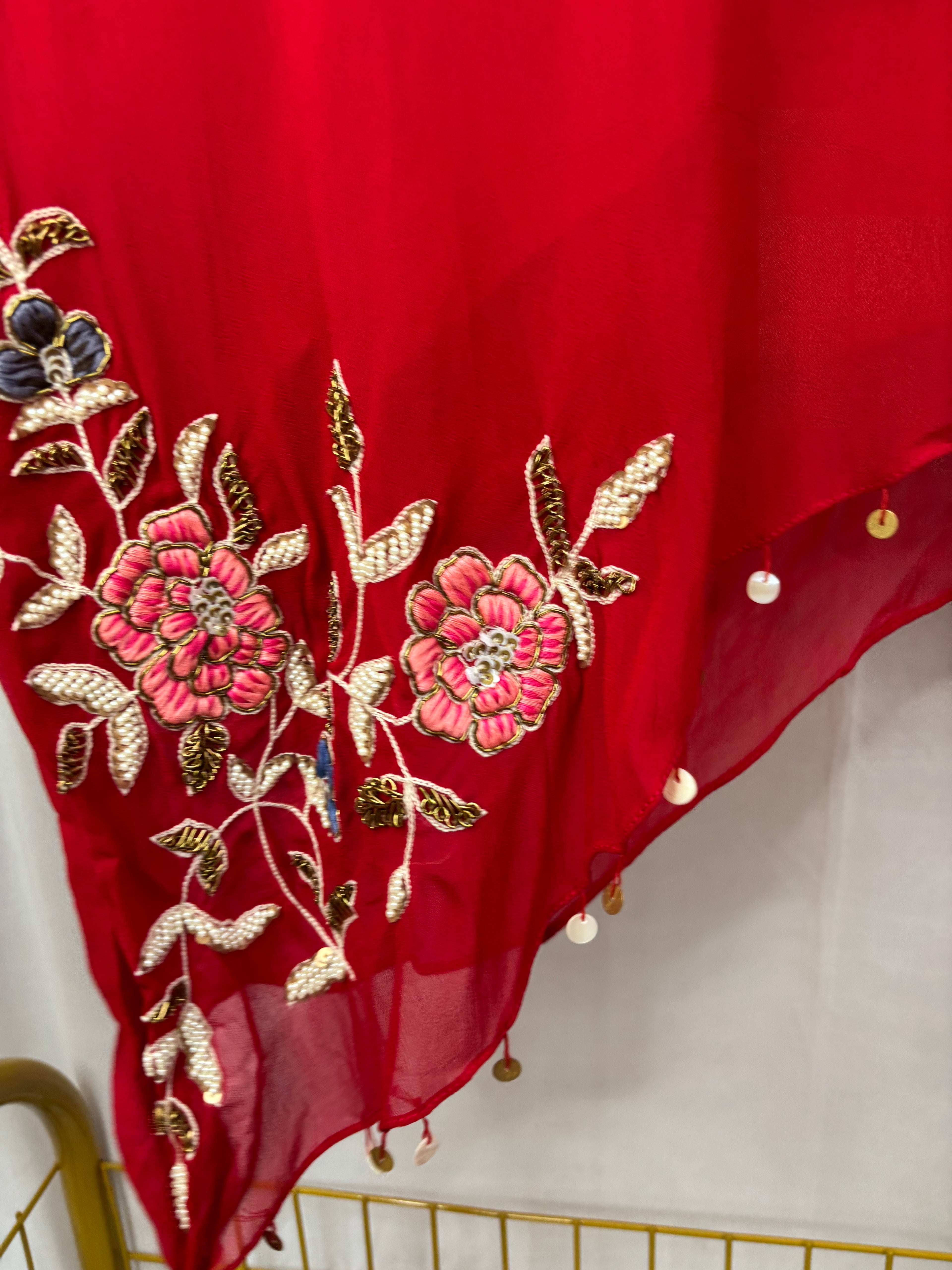 Red fabric with floral embroidery and tassels on a white background