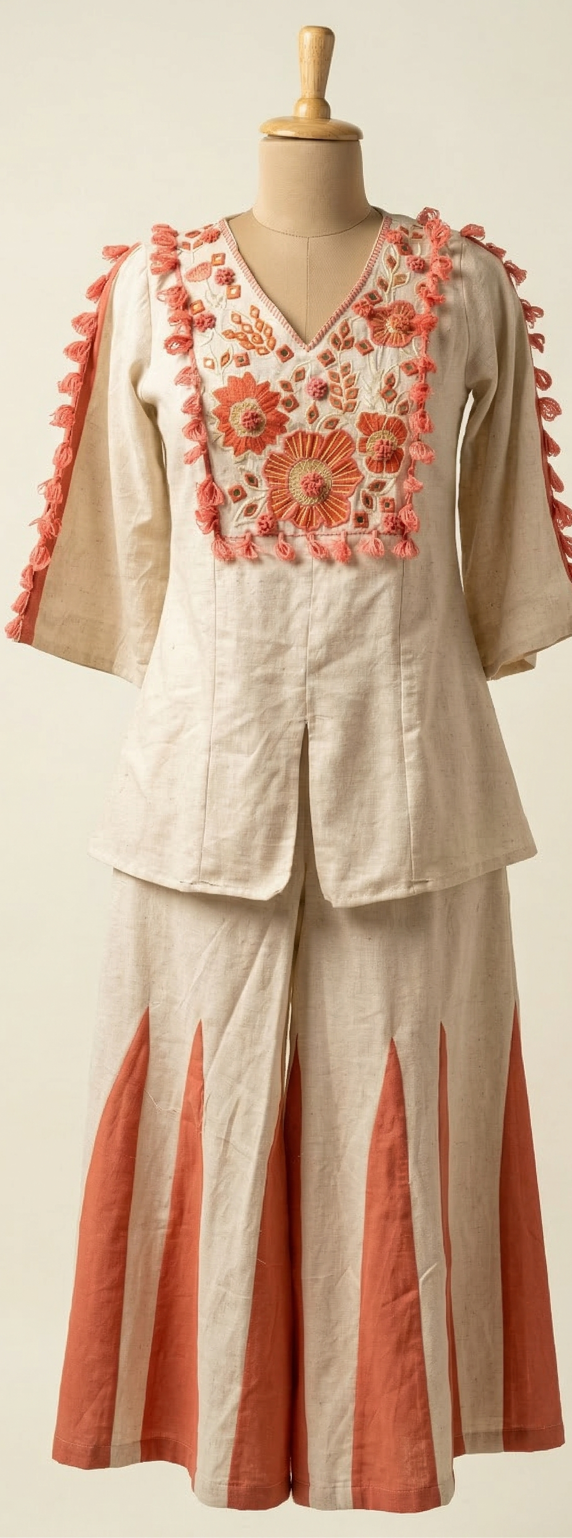Mannequin wearing a beige outfit with floral embroidery and red accents on a plain background